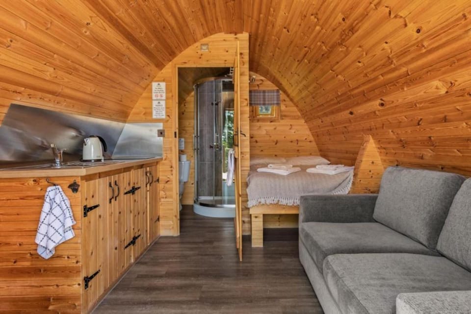 Inside the cosy pod with a comfortable bed, private ensuite, kitchenette and sofa for a relaxing stay.
