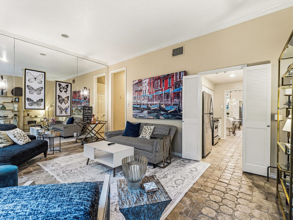 Relax in your stylish living space featuring comfortable seating, vibrant Venice artwork, and an open-concept design connecting to your fully equipped kitchen.