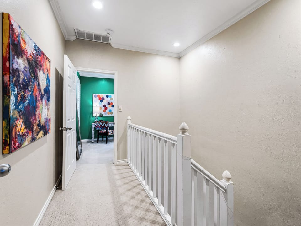 Discover vibrant artwork lining your upstairs hallway, where colorful canvases create an inspiring gallery atmosphere as you move between rooms.