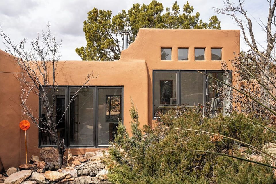 Modern adobe-style building nestled among native vegetation and natural landscaping in a desert setting.