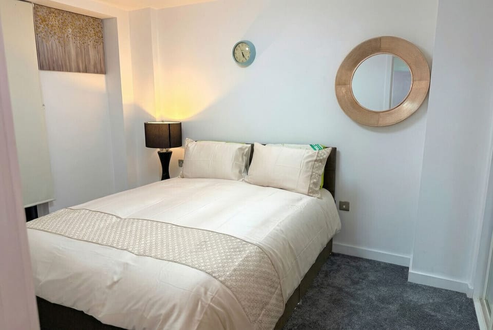 A peaceful second bedroom with fresh white linen and warm bedside lighting, ideal for a travel companion or family member.