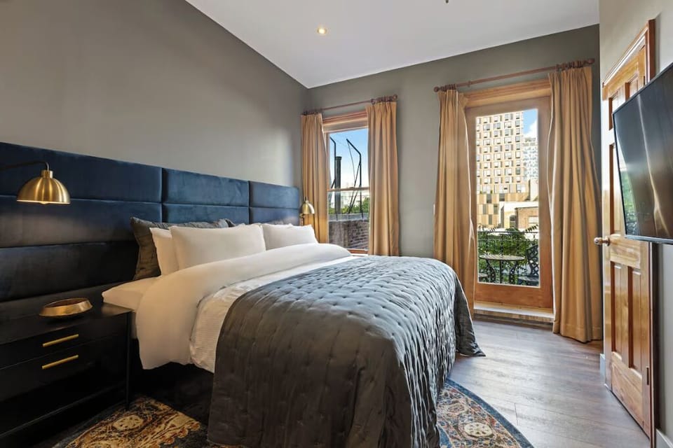 Sink into crisp linens beneath a velvet headboard glow.