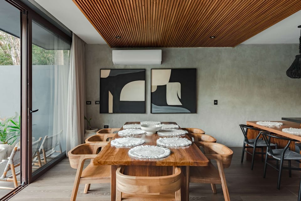 Dining area with geometric black and white wall art, wooden chairs, and natural light.