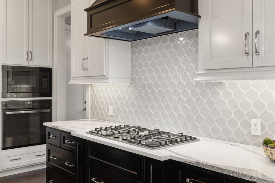 A stunning cooktop centerpiece with a custom range hood and beautifully patterned backsplash, adding a touch of sophistication to everyday cooking.