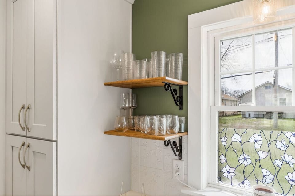 Discover smart storage solutions in this kitchen, boasting a tall, sleek pantry cabinet and beautifully arranged open wooden shelves filled with sparkling glassware.