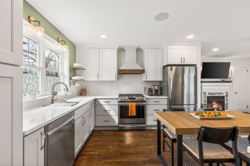 Discover the heart of the home in this sleek, modern kitchen. Boasting pristine white cabinetry, top-of-the-line stainless steel appliances, and a spacious wooden island, it`s an ideal spot for culinary adventures.