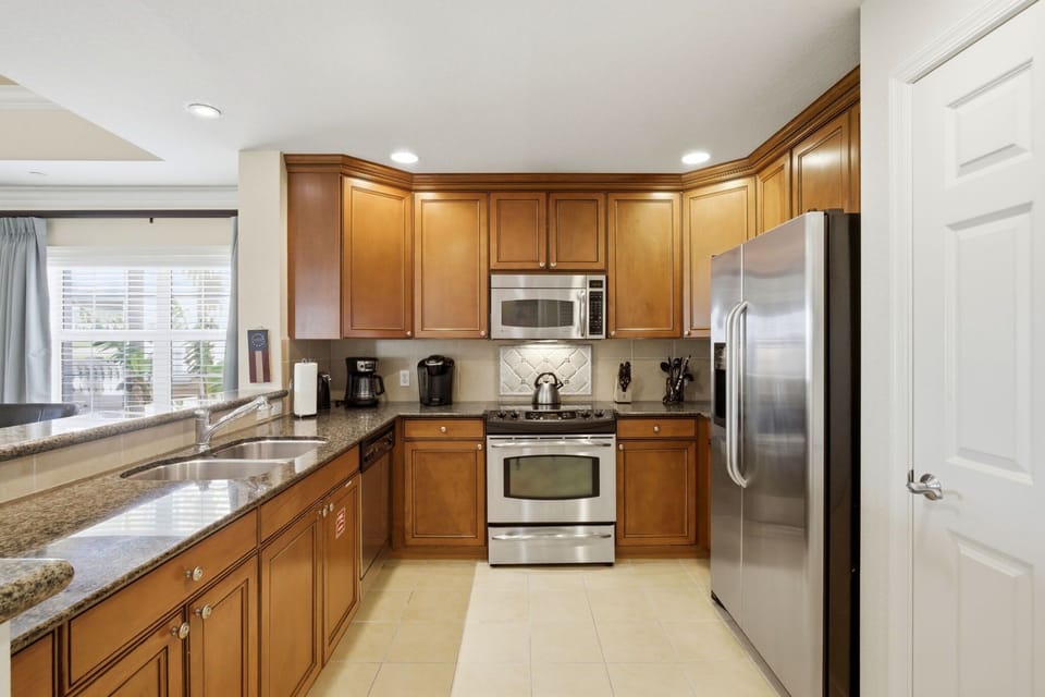 Fully equipped kitchen with granite counters & stainless steel appliances—perfect for family meals or quick breakfasts before the parks