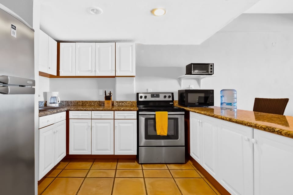 Fully equipped kitchen featuring granite countertops, full-size appliances, and a convenient breakfast bar with seating—perfect for casual meals and easy everyday cooking.