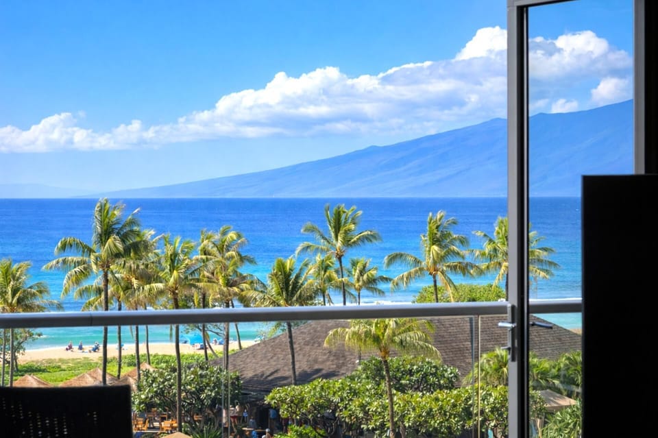 Your elevated lanai frames a postcard view of palm-lined pools and the Pacific, inviting slow mornings with coffee and fresh island air. HKH-515