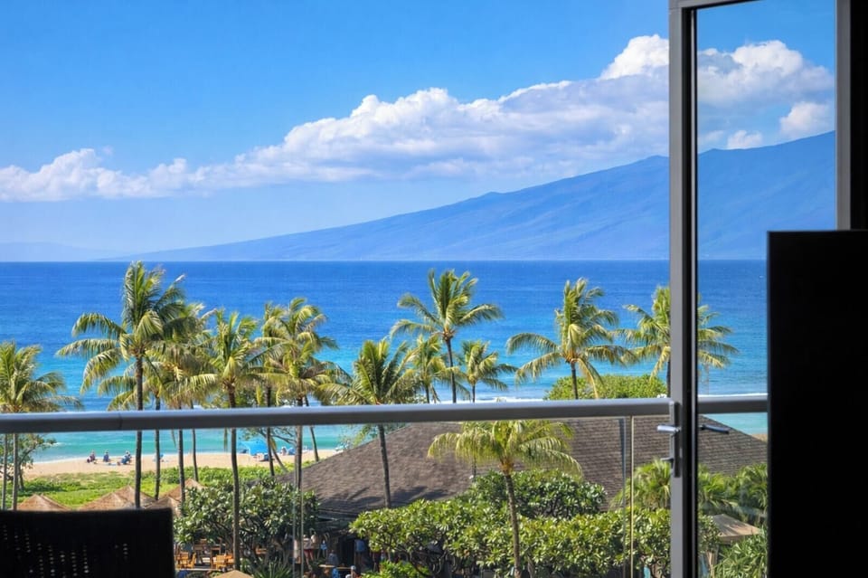 Your elevated lanai frames a postcard view of palm-lined pools and the Pacific, inviting slow mornings with coffee and fresh island air. HKH-515