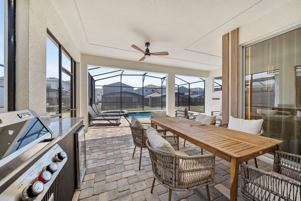 Step outside to a beautifully designed patio with a spacious wooden dining table and stylish wicker chairs. Enjoy the breeze from the ceiling fan as you take in the view of your private pool, ideal for relaxing afternoons.