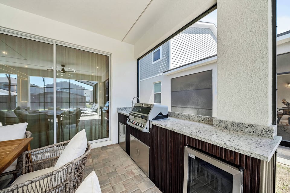 Relax in our charming outdoor dining area featuring natural wood accents and comfy rattan seating. With a built-in grill and sleek granite countertop, it’s the perfect spot for evening gatherings with lovely views and a.