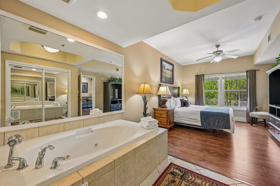 Unwind in your luxurious master suite featuring a romantic jetted tub, plush bedding, and warm wood floors for ultimate relaxation.