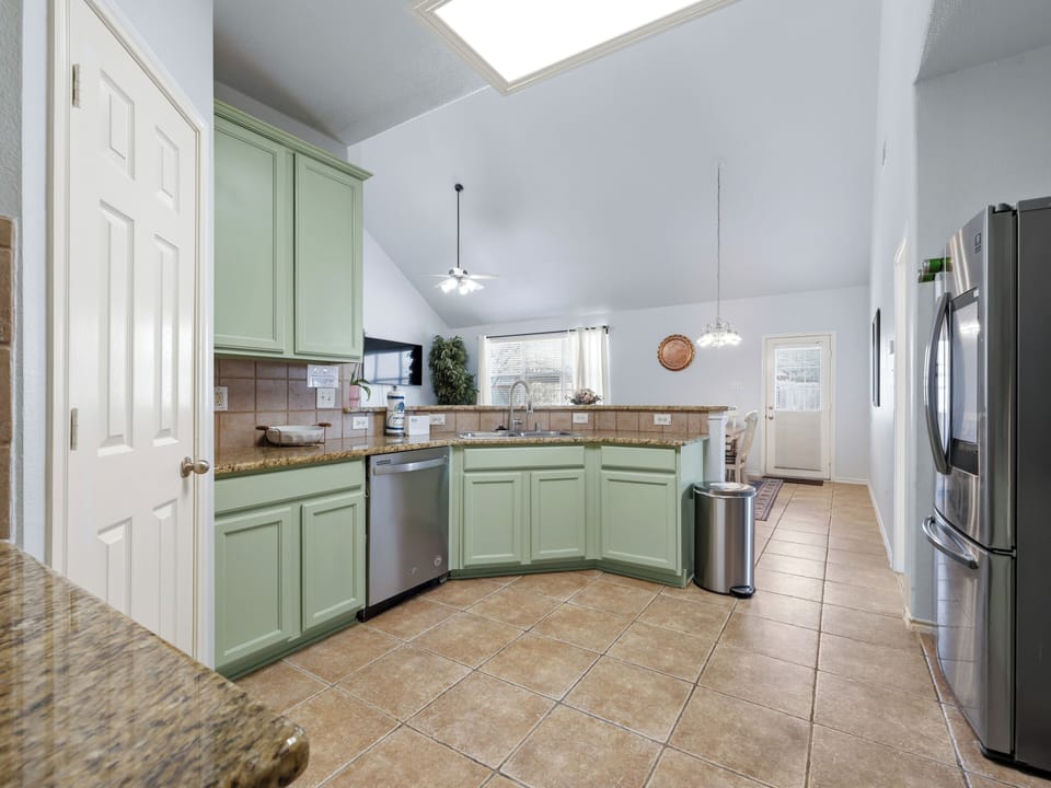 Your fully equipped kitchen features charming mint green cabinets, granite counters, and modern stainless steel appliances perfect for preparing memorable meals together.