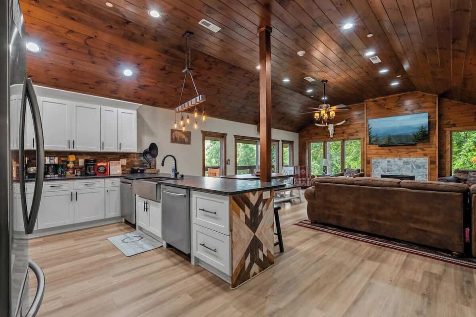Open-concept cabin with vaulted wood ceilings, island kitchen, and cozy fireplace