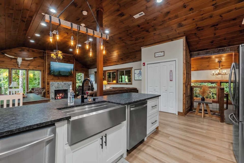 Open-concept cabin kitchen with vaulted wood ceilings and cozy fireplace