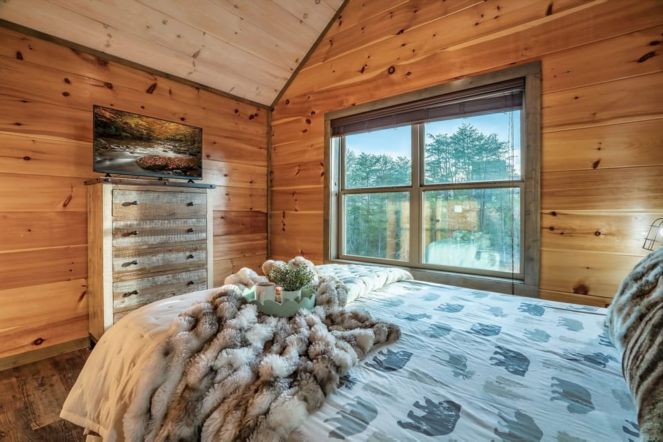 Relax and recharge in this inviting bedroom with natural light and peaceful wooded views.
