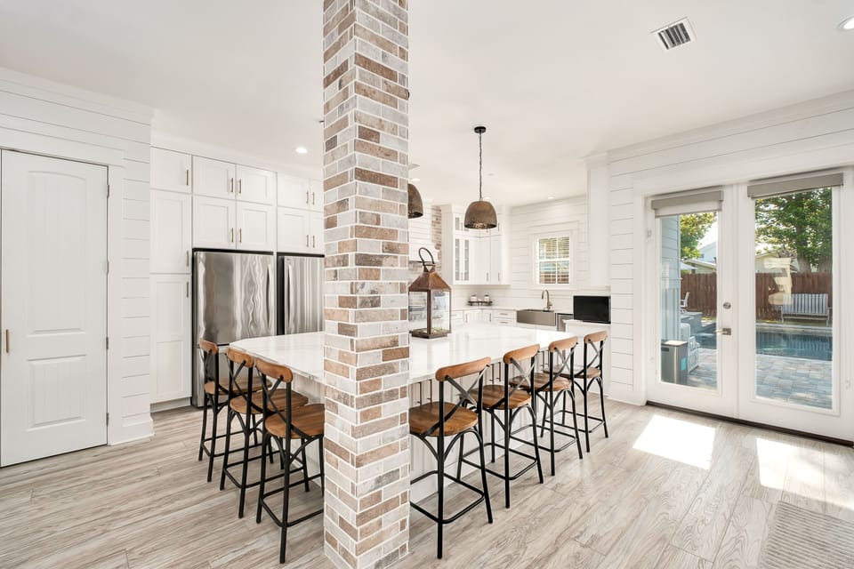 Gather around this bright farmhouse kitchen with charming exposed brick and gleaming countertops—ideal for cooking up memories or sharing morning coffee before splashing into the sparkling pool just steps away.