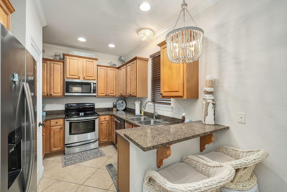 Step into your fully equipped kitchen with granite countertops, stainless steel appliances, and a coastal-chic chandelier that sets a welcoming, beachy mood for your stay.