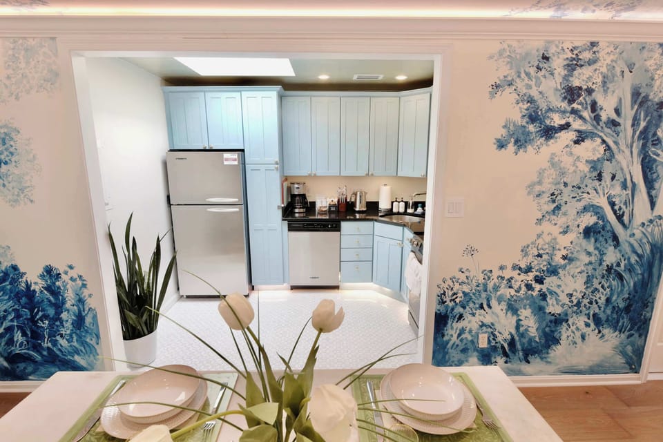 Kitchen framed by blue landscape murals, blending everyday convenience with a gallery‑like backdrop.