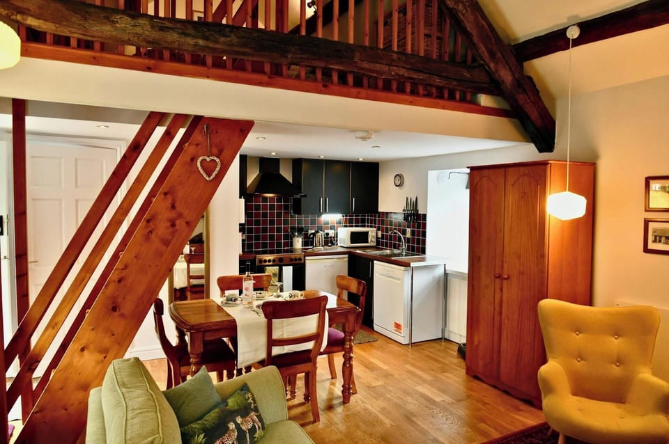 Open-plan room with wooden beams, dining table and kitchen units