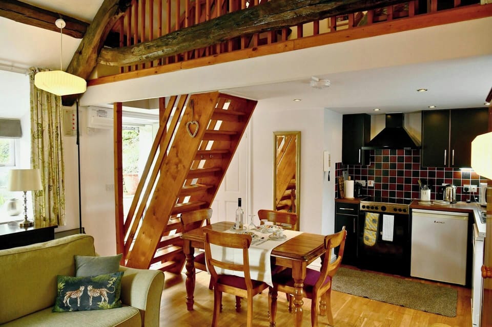 Open-plan living room with wooden staircase, dining table and kitchen area