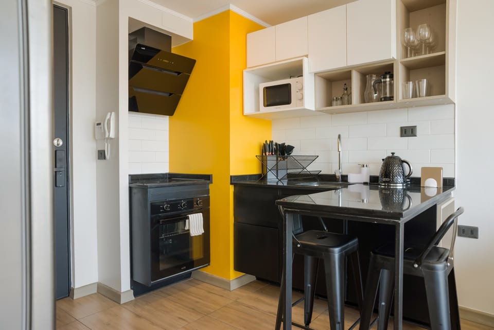 Sleek and modern kitchen with vibrant yellow accents and all essential amenities for a comfortable stay.