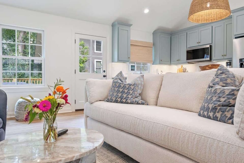 Bright living area w/ plush sofa, patterned pillows & natural light