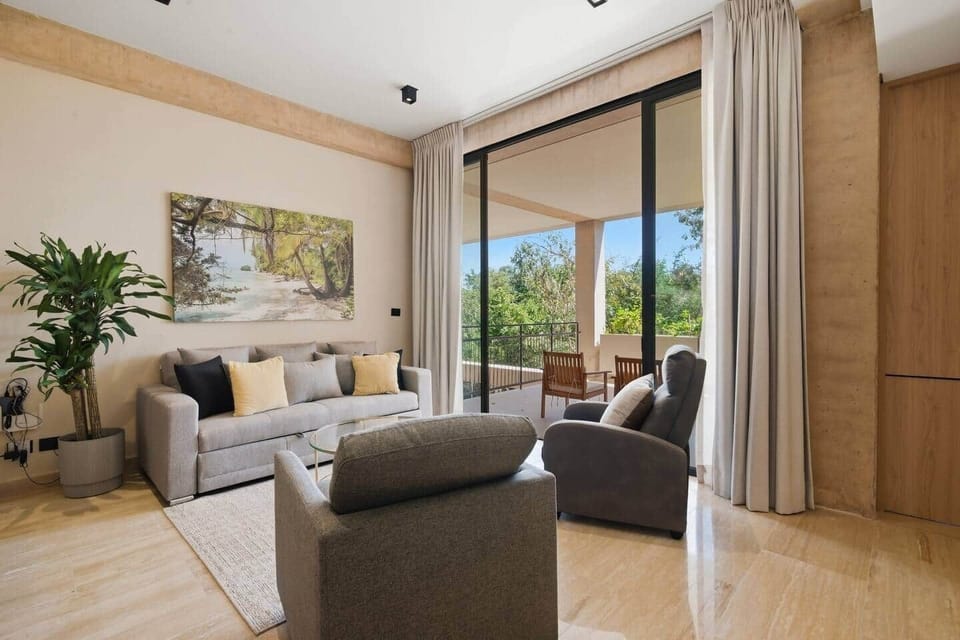 Inviting living room featuring a comfortable sofa bed for extra guests, with direct access to your private terrace overlooking lush greenery, perfect for relaxing and enjoying your stay.