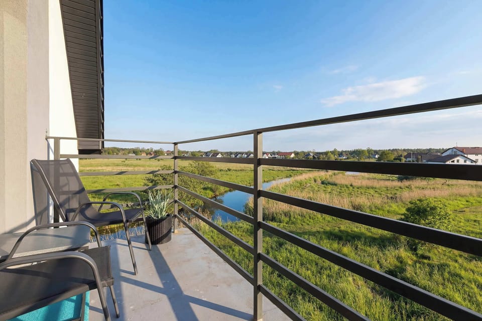 The private balcony is equipped with two black chairs and a small table, offering a peaceful spot for outdoor relaxation.