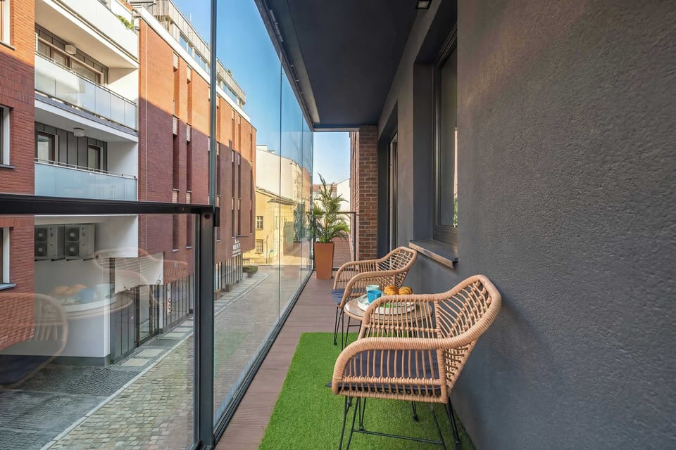 A secondary balcony perspective captures the long, narrow layout of the outdoor area, showing the artificial grass and neighboring brick architecture.