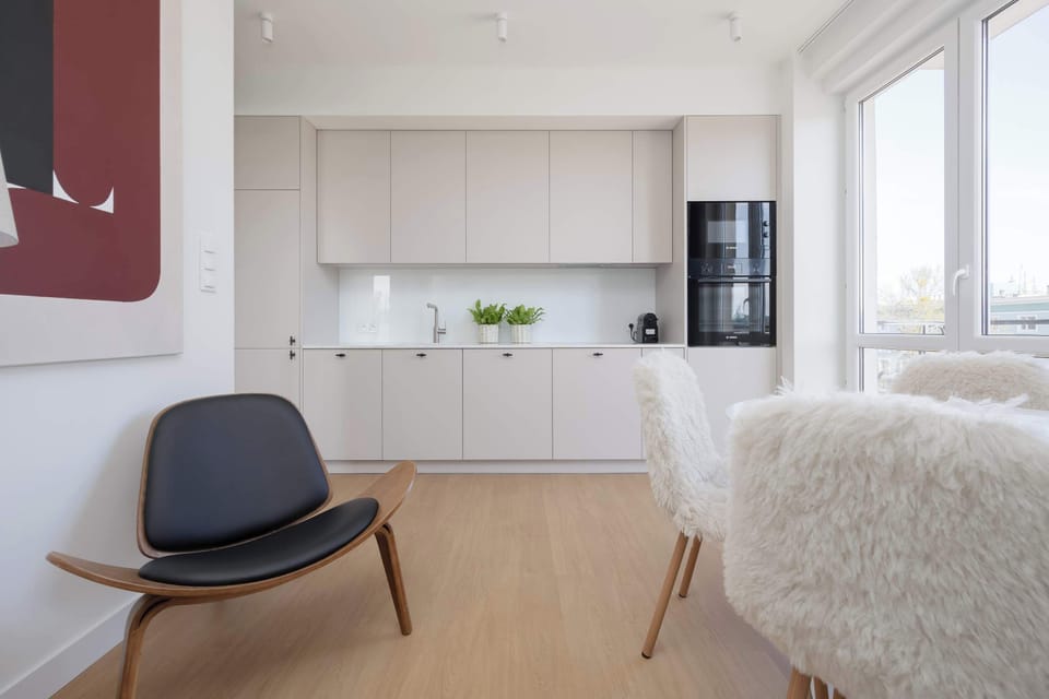 A compact dining area with a table and chairs positioned next to a sleek kitchenette. The layout is practical and ideal for everyday meals.