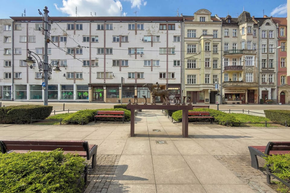 An exterior town view captures a row of colorful historic buildings and a modern apartment block, reflecting a diverse urban environment.
