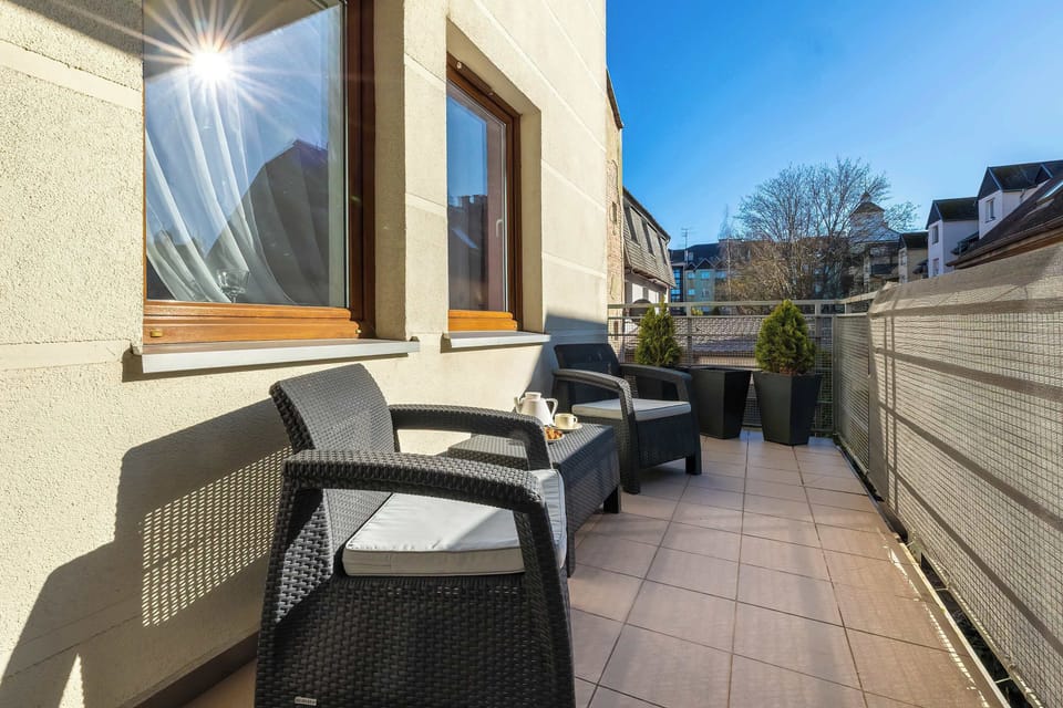 Another balcony view showing chairs and table, surrounded by building walls. It provides a private outdoor area.