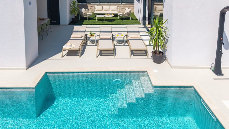 An aerial view shows the 7m x 3m heated pool and the cozy outdoor lounge corner for relaxation.