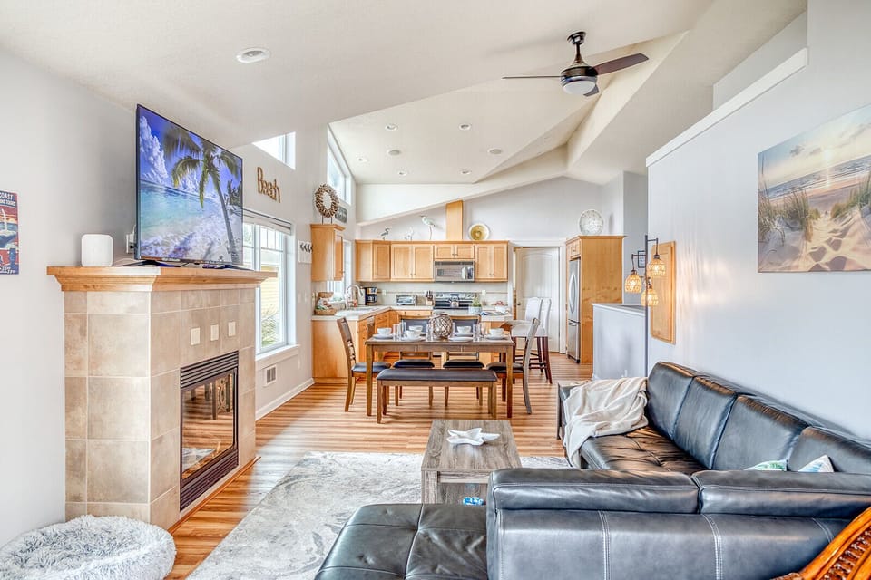 Unwind in your open-concept living space featuring leather seating, a cozy fireplace, and modern kitchen—perfect for memorable evenings together.