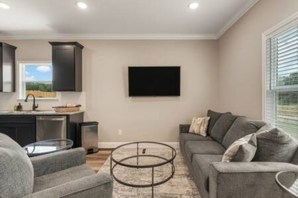 Unwind in this spacious living room, bathed in natural light. Perfect for cozy family movie nights or relaxing after a day of exploring. Enjoy comfort and style.