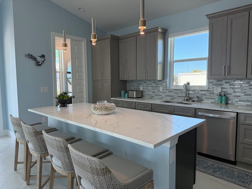 Cook your favorite meals in this elegant kitchen with gleaming quartz countertops, premium appliances, and coastal-inspired design details.