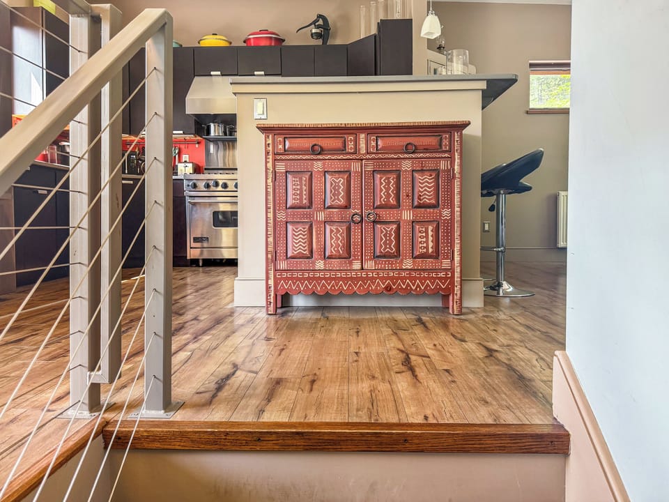 Modern cable-railing stairway leads to the main level social hub. This bright landing features curated designer furniture and offers a first glimpse into the open-concept living, dining, and kitchen areas at the heart of The Crag.