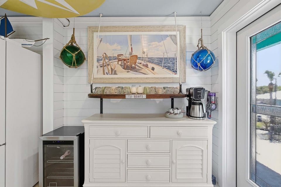 Enjoy your beach stay with this charming coffee bar featuring nautical décor, wine fridge, and coffee station. A perfect spot to start your day or unwind, blending coastal style with convenience and relaxation.