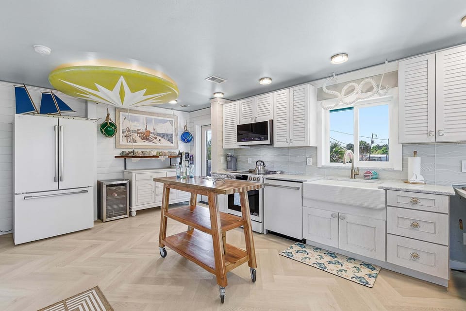 Charming coastal kitchen with modern appliances, farmhouse sink, and island workspace. Perfect for a beach stay, enjoy a bright, airy space designed for easy meals and relaxed gatherings after a day by the shore.