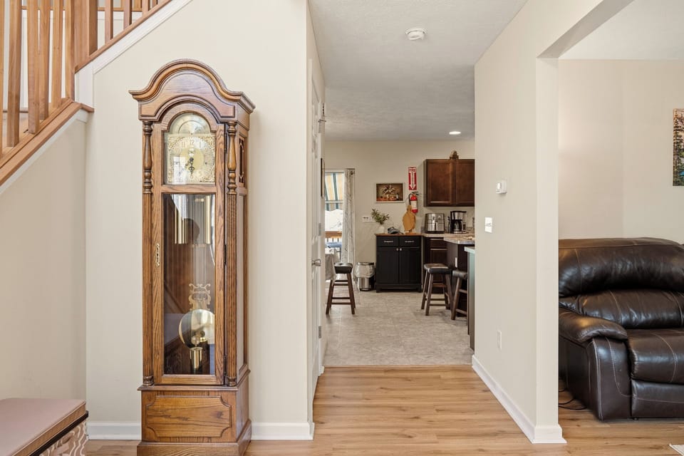 Warm entryway with a classic grandfather clock leading into an inviting open kitchen and living area.