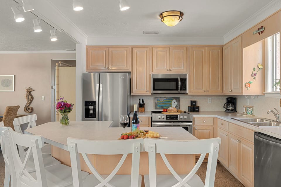 Bright modern kitchen with light wood cabinetry, stainless steel appliances, and a welcoming island set for wine and bites.