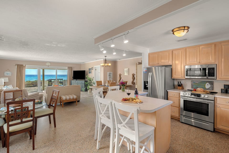 Bright coastal living room with comfy seating, ocean views, and sliding doors that open straight to the beach.
