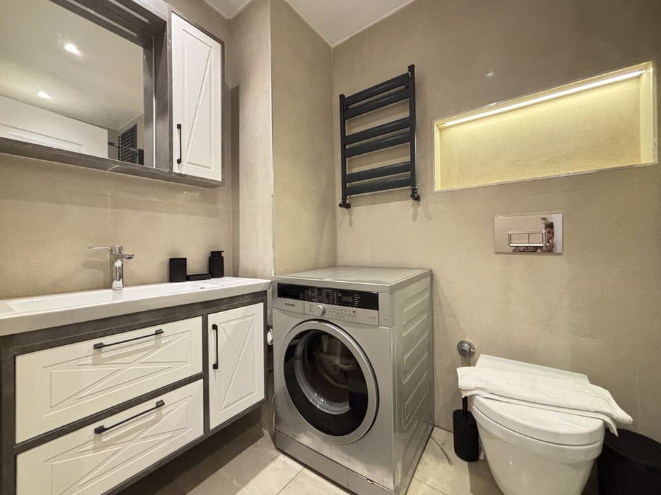 Bathroom with a washing machine, vanity and toilet.