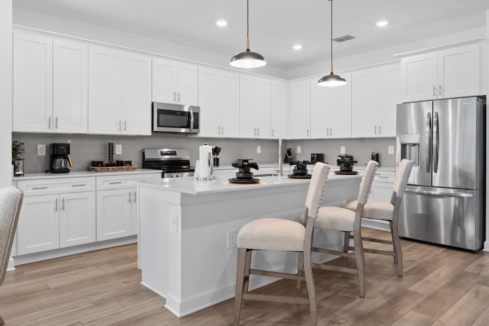 Your spacious modern kitchen features white cabinetry, stainless steel appliances, and a central island where you can prepare meals and gather with loved ones.