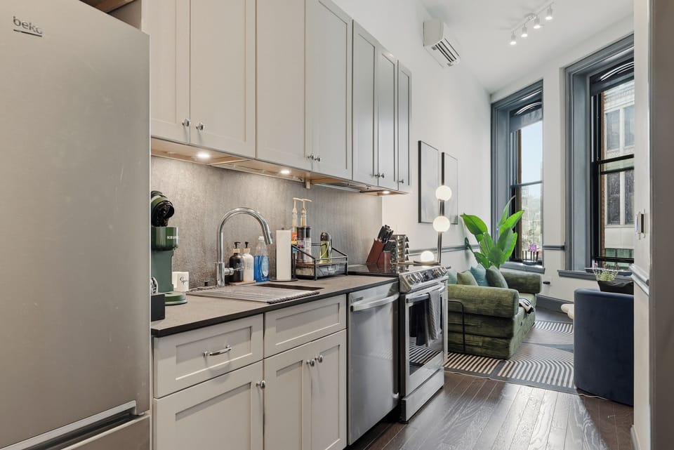 Sleek galley kitchen & bright lounge with high ceilings, tall windows