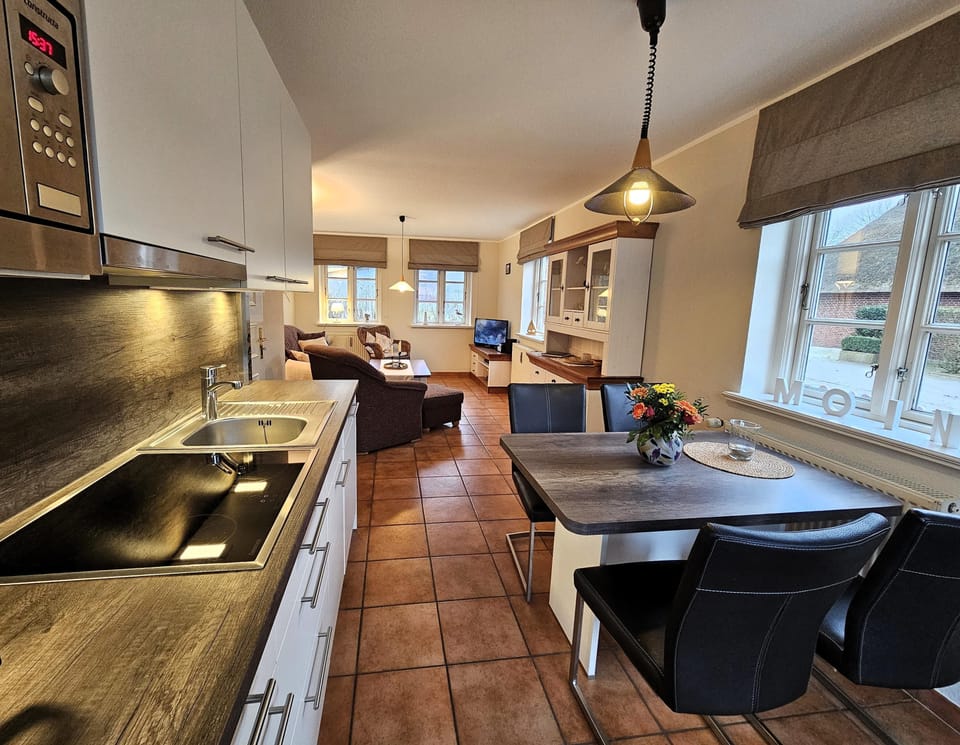 Modern kitchen with dining table and living area in the background.