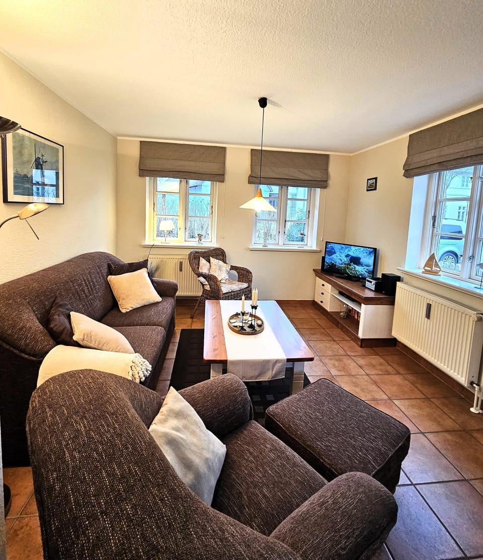 Cozy living room with sofa, armchair, and TV.