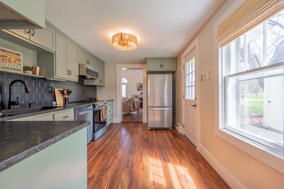 This stylish and functional kitchen is a chef’s delight, featuring a sophisticated color palette and modern updates. The sage green cabinetry provides ample storage and pairs beautifully with the dark countertops and charcoal tile backsplash.
